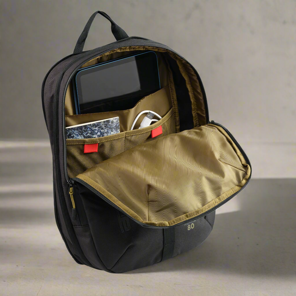 Black backpack with open front compartment showing electronic devices on a neutral background