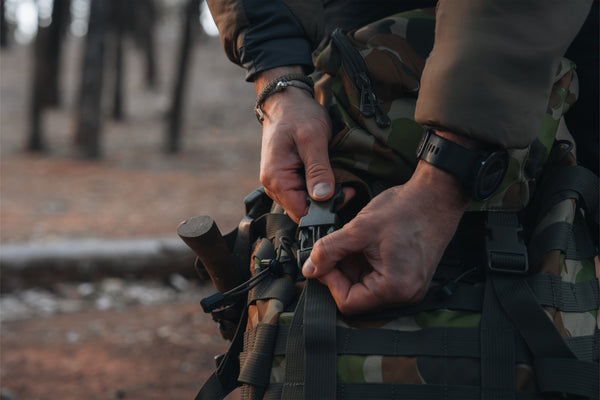 Person adjusting a rucksack with a forest background