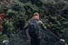 Person with a backpack walking on a suspension bridge in a forest