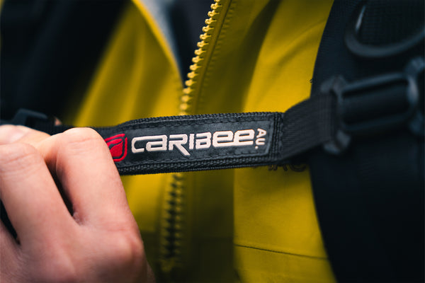 Close-up of a yellow jacket with a Caribee logo on a black strap.