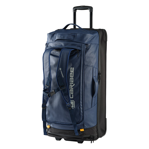 A blue Caribee Odyssey Hybrid 100L wheel travel bag with concealable shoulder straps exposed. Features telescopic handle, top and side carry options, and all-terrain wheels.