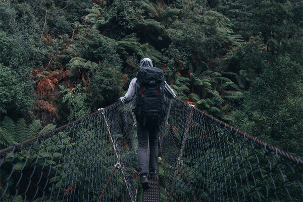 Person with a Caribee rucksack crossing a suspension bridge in a forest