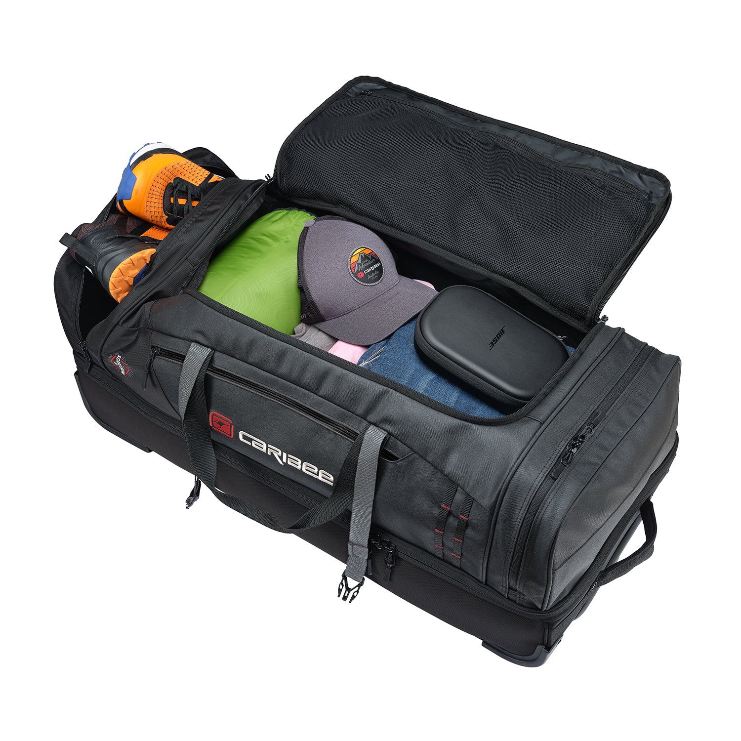 A black Caribee Scarecrow 85 bag shown open, filled with gear including an orange and black helmet, a green bag, a gray cap, and blue jeans, on a white background.