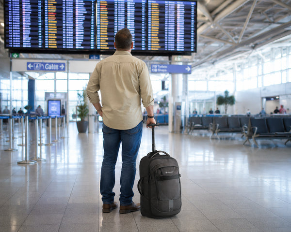 Man with a Caribee Adventure 40 standing in an airport terminal looking at the departure board.