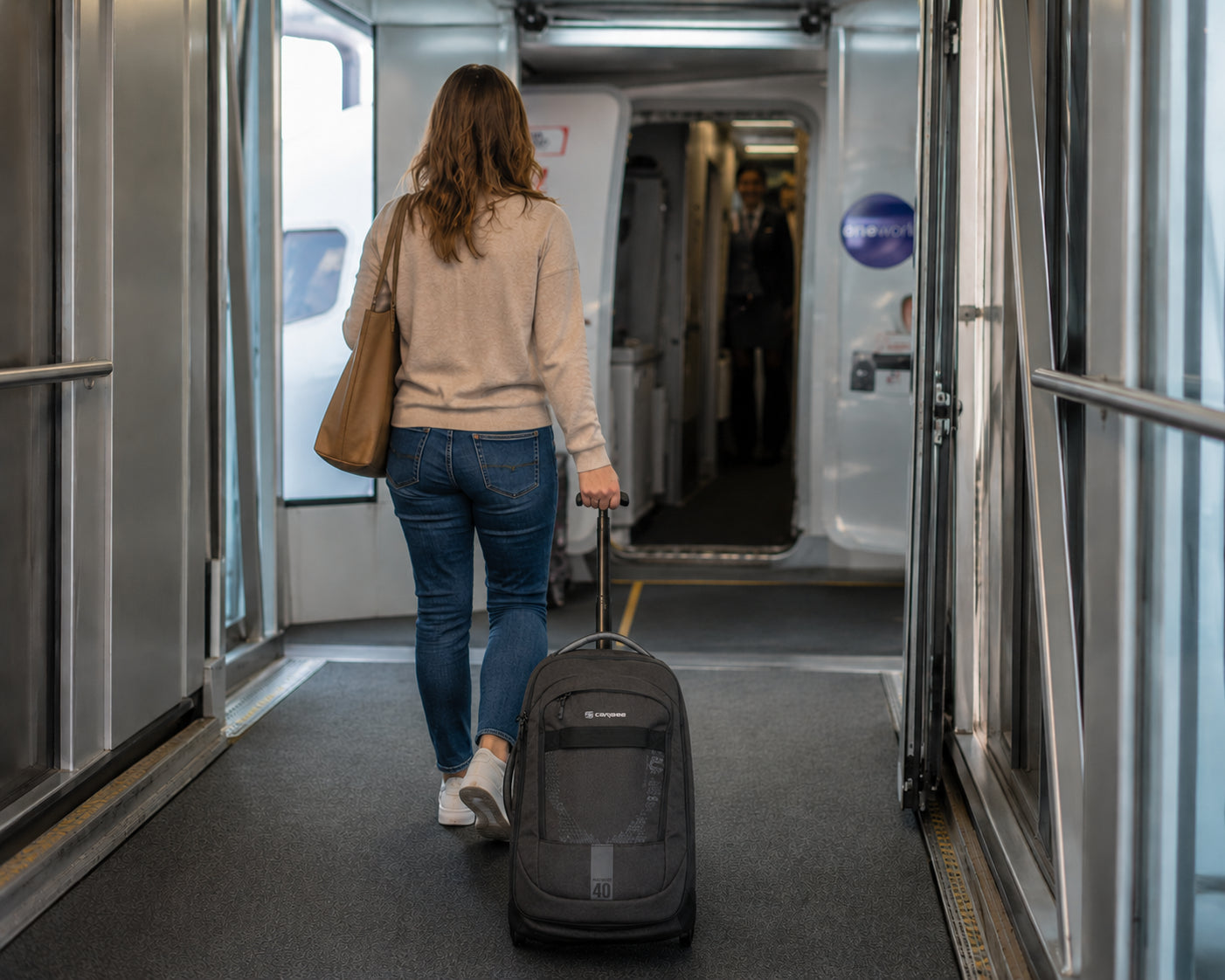 Woman with a Caribee Adventure 40 wheel aboard bag walking to an airplane door to board