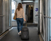 Woman with a Caribee Adventure 40 wheel aboard bag walking to an airplane door to board